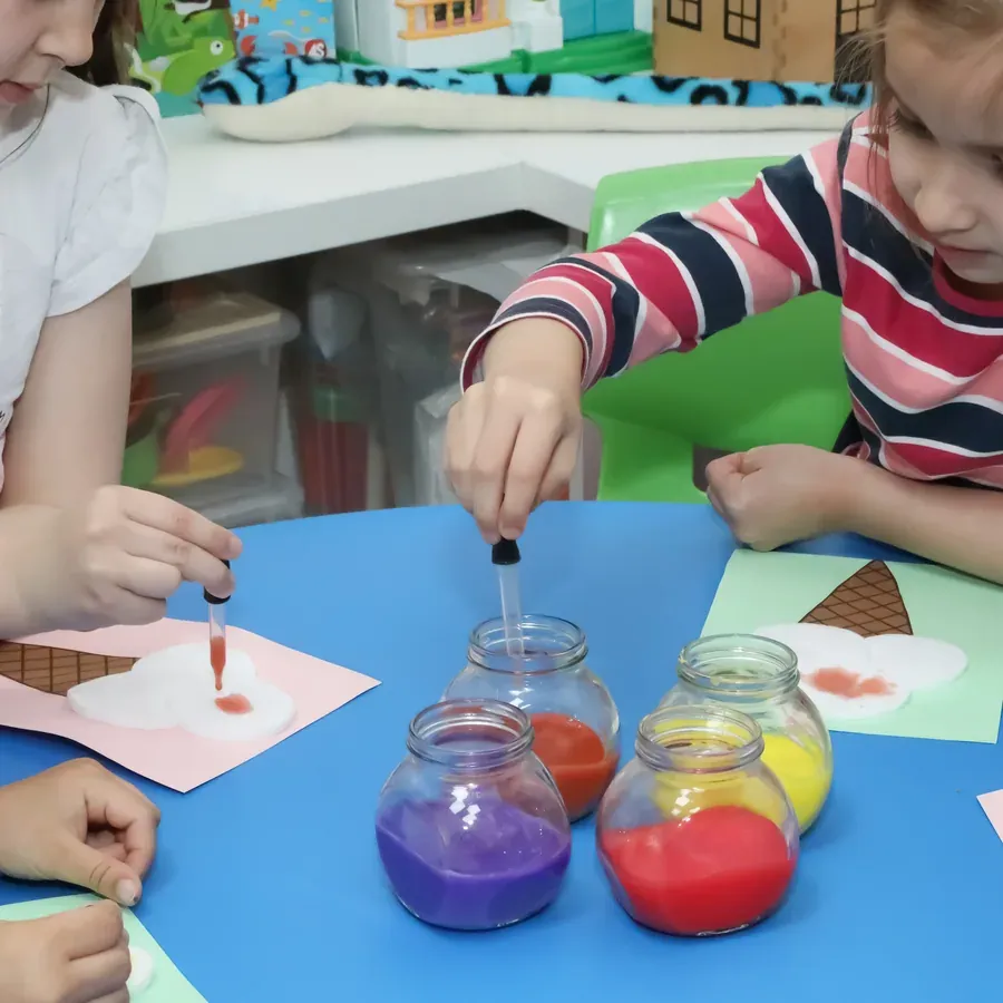 Fetiță picurând culoare dintr-o pipetă, la atelierul de artă